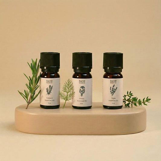 Three Base Remedies essential oil bottles with packaging, highlighting rosemary, fennel, and thyme in minimal natural light.